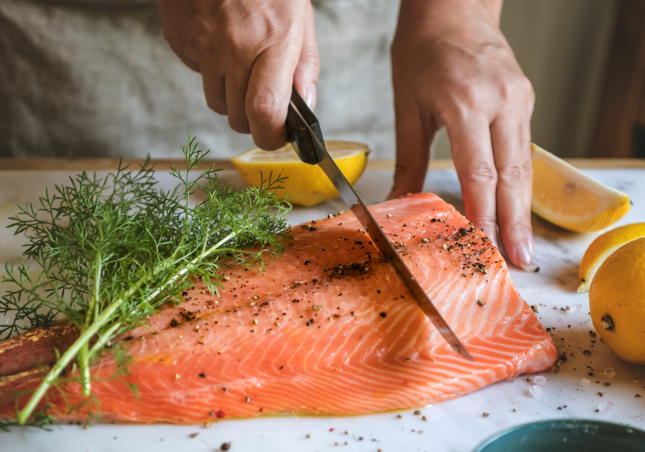 person slicing salmon board in a kitchen on a cutting board